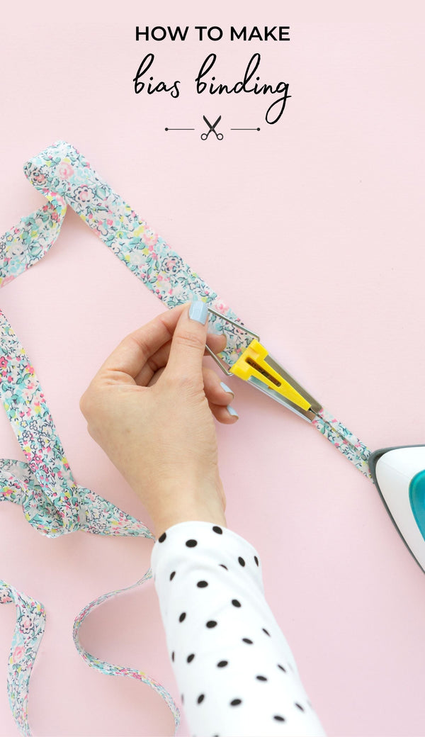 Hands pulling a strip of bias binding through a bias binding making, with an iron pressing, with the title text 'How to Make Bias Binding'