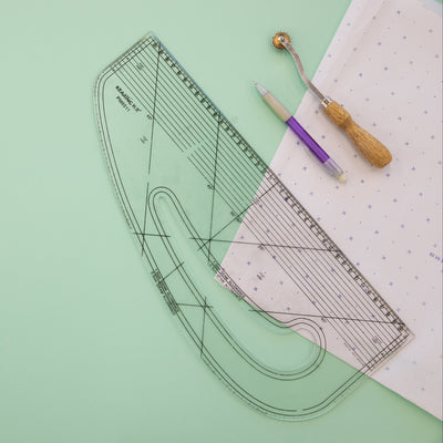 Pattern paper with cutting guide and tools on a green surface