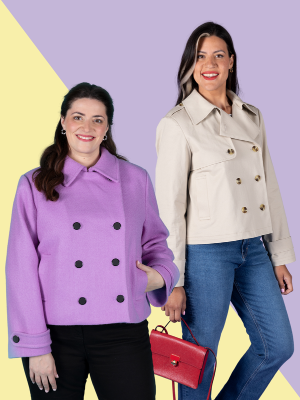 Two women modelling Manon jackets against a split yellow and lilac background. The woman on the left wears a purple pea-coat-style jacket with black buttons and black trousers. The woman on the right wears a classic beige trench-style jacket with blue jeans holding a red handbag.